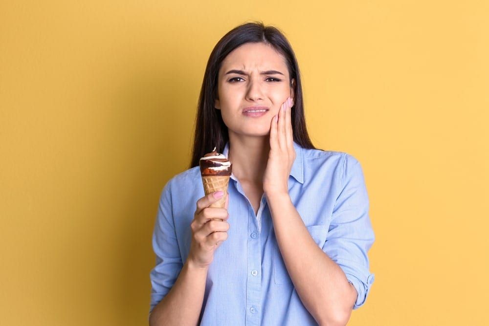 woman eating an ice cream cone with a pained expression