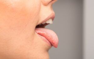 Woman sticking out tongue side profile
