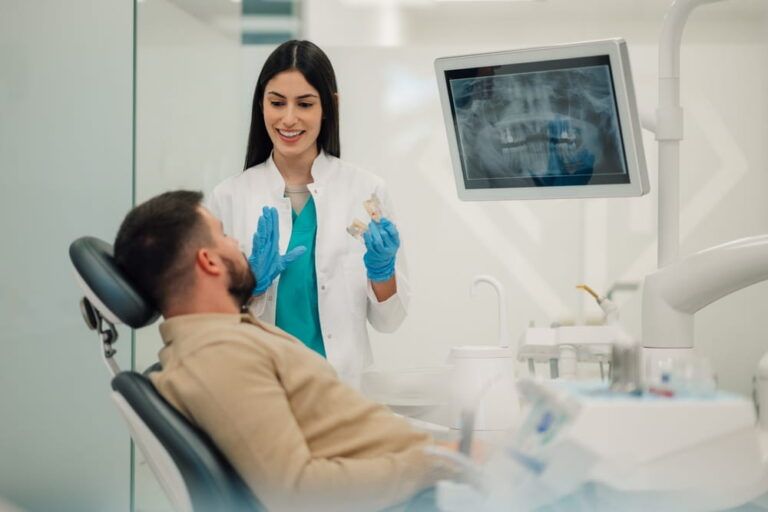 Female dentist wearing gloves showing a dental x ray on a monitor
