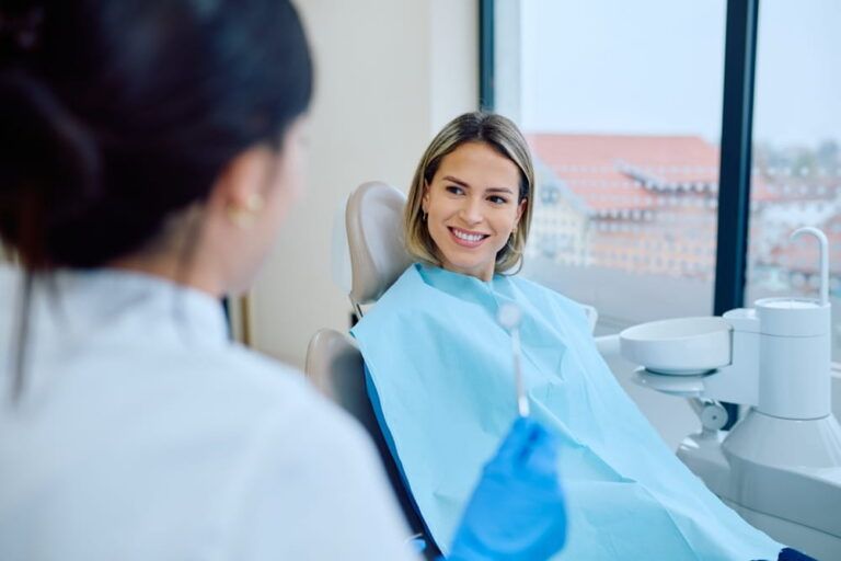 Young woman sitting in a dental chair, smiling and listening to her dentist at a modern dental office